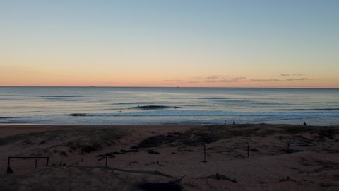 Drone shot of afternoon surfers with orange sunset on ocean waves Shelly Beach Central Coast NSW Australia 4K