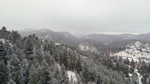 Drone Aerial View Flying Over Snow Covered Pine Tree Hills And Mountains Winterscape Near Kittredge Evergreen Colorado