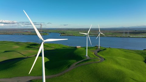 Wind Turbines producing energy on green hills near Delta River in Rio Vista Northern California
