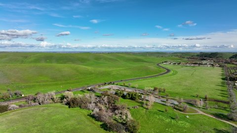 Aerial view of Marsh Creek road winding through green hills against blue sky Brentwood, California