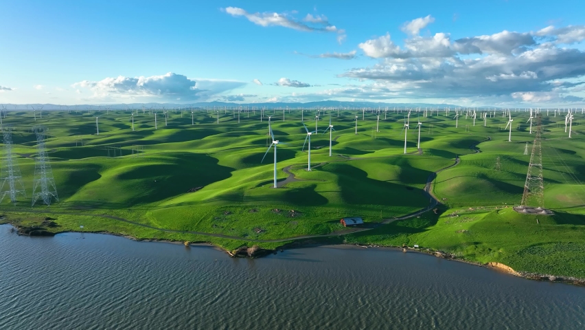 Wind Turbine Farm producing Clean energy along river with rolling green hills, Montezuma Hills California Royalty-Free Stock Footage #1084299493