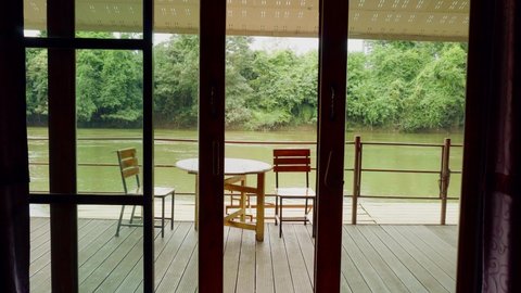 Kanchanaburi , Thailand - 11 18 2021: Patio deck from inside a luxury riverboat, in the background the fast flowing Khwae Noi River passes by in Kanchanaburi, Thailand 