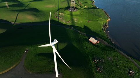 High Angle above Wind Turbine propeller spinning on Rural green hills with Red barn along river, Montezuma hills, California