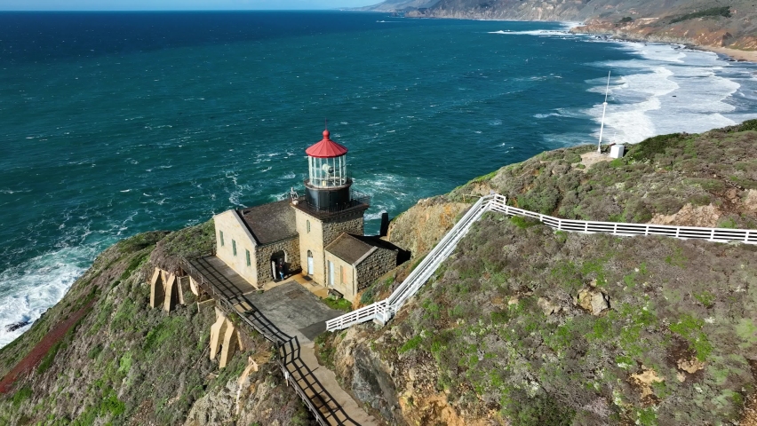 Aerial shot of Point Sur Lighthouse on Sea cliff against blue ocean waves, Big Sur California