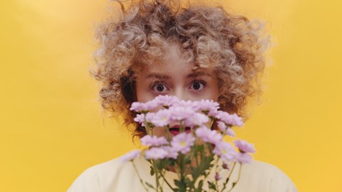 Close Up Portrait of Young Curly Female With Gerbera Daisy Flowers and Confused Facial Expression, Full Frame Slow Motion