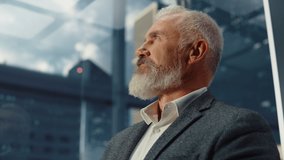 Portrait of Successful Middle Aged Businessman in a Suit Riding Glass Elevator to Office in Modern Business Center. Male Looking at Modern Downtown Skyscrapers Out of the Panorama Window in the Lift. - Powered by Shutterstock - Get 15% off with code: PIKWIZARD15