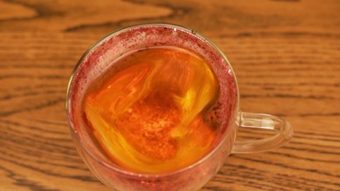 Natural Tea for Lover in Cup in Shape of Heart with Love, Close-up. Female Hand Puts Beautiful Cup Of Iridescent Tea On Wooden Table.