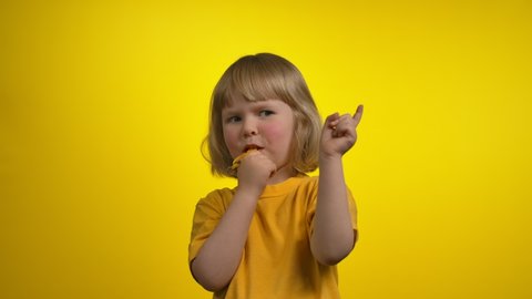 Little girl with short hair is blowing in a whistle and pointing to the camera