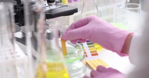 Scientist chemist checking acidity of liquid in petri dish using litmus paper in laboratory closeup 4k movie