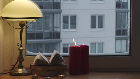 Warm light of a vintage lamp with an open book and candles. Scandinavian interior and understanding of comfort and happiness