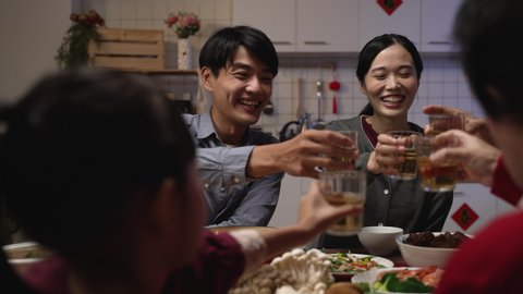 selective focus of happy young asian couple drinking toast with tea to their family at chinese chinese lunar new year reunion dinner at home. chinese text translation: fortune