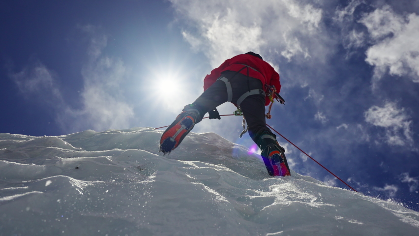 Alpinist equipped with red crampon climb over ice wall under blue sunny sky Royalty-Free Stock Footage #1084322476