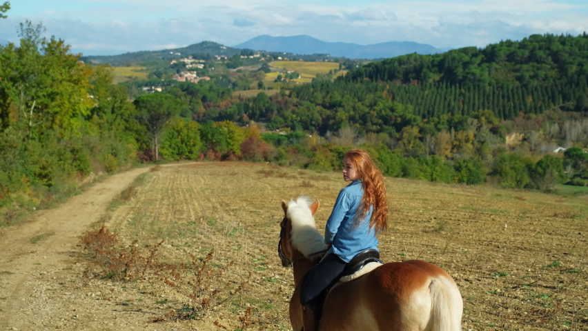 Young woman riding on horse through idyllic landscape
