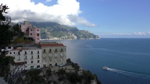 Various transport moving at three different altitude levels on Amalfi coast, motorboats in the sea, cars and bus on two steep cliff roads just above beach of Castiglione of Ravello village, high angle