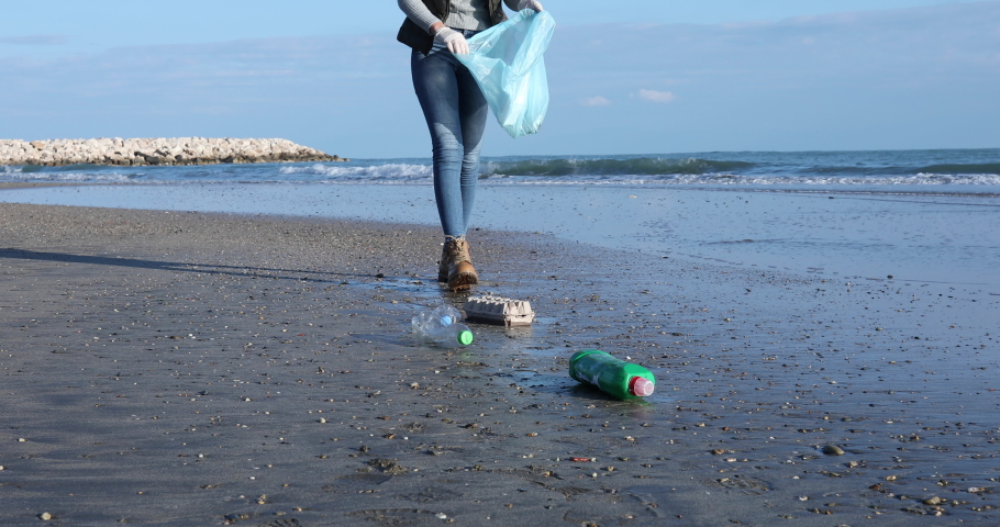 young woman picking pet bottles at the beach Royalty-Free Stock Footage #1084327429