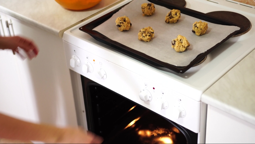 Girl puts in the oven a baking sheet with American cookies with chocolate chips Royalty-Free Stock Footage #1084330201