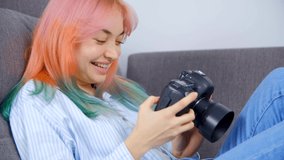 Creative young photographer girl browsing photos on professioinal dslr camera. Cute female with dyed hair watching images on digital photocamera after photoshoot with great excitement. 4k stock video