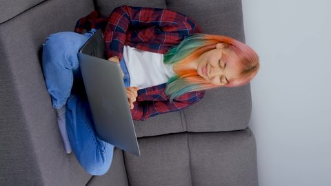 Freelancer girl with colored hair working from home. Free lance writer female with dyed hair typing text on laptop computer while sitting in apartment on lockdown. Stock video of free lancer in 4K