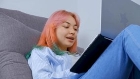 Stock video of freelancer girl with dyed hair working on notebook computer at home on lockdown. Young woman with colored hair typing text on laptop keyboard filmed in 4K ultra hd