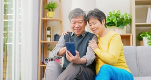 asian elderly couple check social media by mobile phone in living room at home
