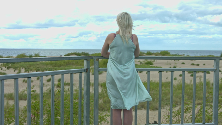 A young lonely woman is standing outside, she is grief-stricken. A sad woman looks into the distance. Rear view of depressed woman.