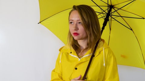 A girl in a yellow raincoat under an umbrella calls to her. Isolated on white background.