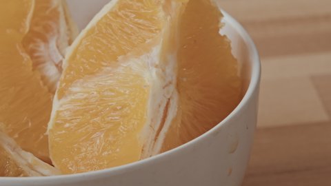 Extreme close up with tracking of juicy orange pieces in bowl