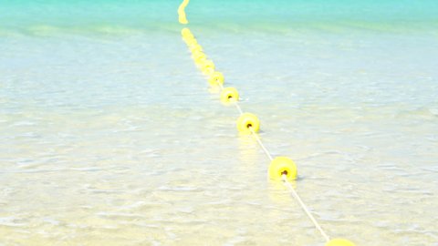 Buoyant swim lane section divider safety line. Yellow marker swim area buoys on sea. Yellow floating buoy over ocean.