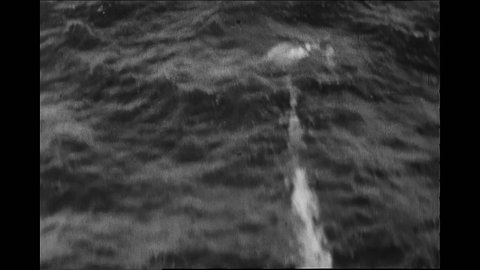 1940s: Submarine fires torpedo at ship. Explosion. Ship.