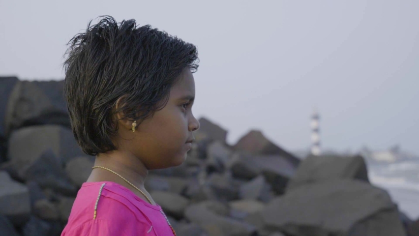 Girl looking at ocean at sunset. Asian girl 10-12 years old.