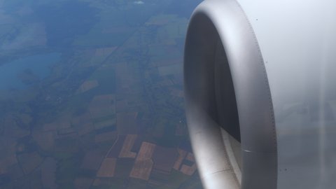 Flying turbine is spinning a motor. Clouds float across sky at high altitude. Flight above ground. View of the turbine of the aircraft and the off on runway. airplane in flight, view from plane window