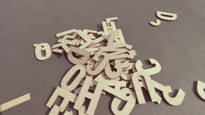 Close up hand picking up White Word Wooden Letters Alphabet for Art Crafts Home Decor spread on table. DIY Design decoration background Concept.