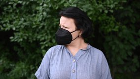 Woman in medical mask outdoors. Static camera.