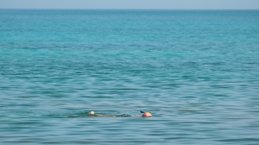 Unrecognizable man swimming with snorkeling breathing mask under sea water surface