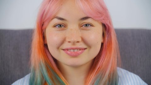 Individual girl with dyed hair smiling in camera. Stock video portrait of cute young woman in late 20s with colored hair. Cute female model posing for royalty free video in 4K ultra hd
