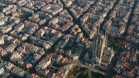 Aerial view of unfinished Expiatory Temple, Church, Basilica of the Sagrada Familia in Barcelona, Catalonia, Spain. Cityscape with octagon buildings. Sunny day. Urban traffic on streets. Slow motion