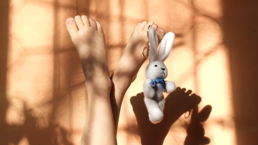 Fashion hipster flat lay with jeans , bunny toy and female bare foot on orange coral background with shadows lines