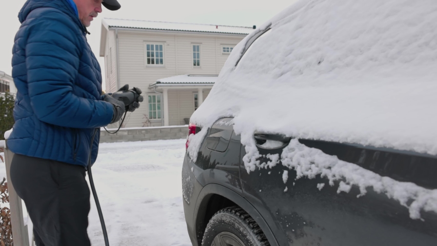 Beautiful view of a man connecting a charging cable to an electric car charging station on a frosty winter day. Sweden. Royalty-Free Stock Footage #1084400851
