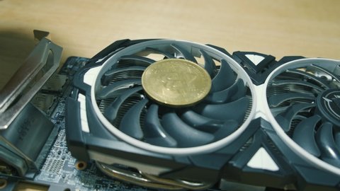 Black Graphic card with BTC golden coin and rotating fan Ehtereum Crypto mining rig