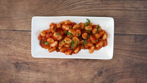 Serving a Plate of Gnocchi with Tomato Sauce