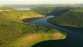 Panoramic view of the meandering river flowing through the green hills from a bird's eye view. Location Dniester River, Ukraine, Europe. Cinematic drone shot. Filmed in UHD 4k video. Beauty of earth.