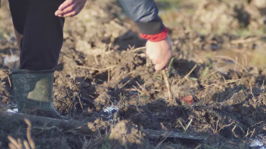 a man turns the dirt with a stick.