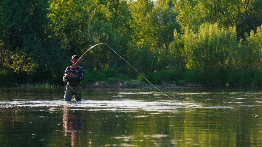 Fly fishing. Man fly fishing on the wild river with lots of insects flying in the air Royalty-Free Stock Footage #1084410835