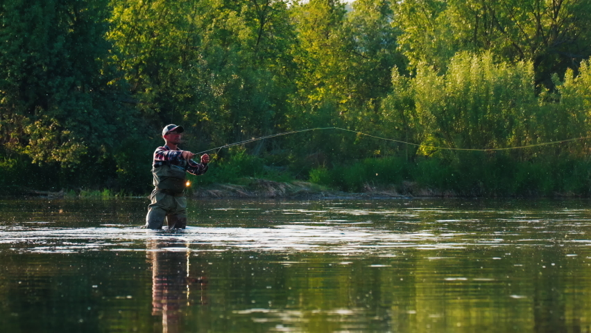 Fly fishing. Man fly fishing on the wild river with lots of insects flying in the air