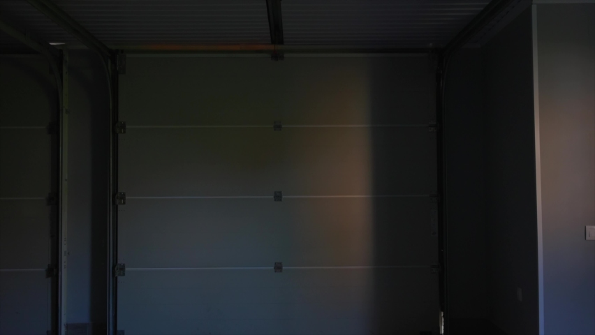 Lifting automatic gates. An automatic garage door opens, revealing a view of the courtyard. Lifting the door with roller shutters Royalty-Free Stock Footage #1084410949