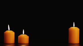 Three yellow beautifully burning candle on a black background. Copy space. Video screensaver, intro, footage for titles and captions. Holiday halloween, new year, christmas, romance and memory. UHD 4K