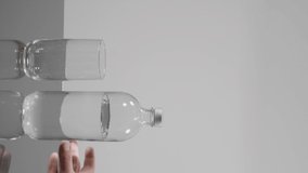 Full water bottle and glass. The background is white. Water is filled from the bottle to the glass. There is space to write. Vertical video.