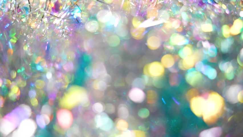 Close-up view abstract 4k stock video shiny gradient bokeh Christmas background of multicolored holiday decorations out of focus. Silver, gold, blue, green, yellow, purple colors changing and shining Royalty-Free Stock Footage #1084416817