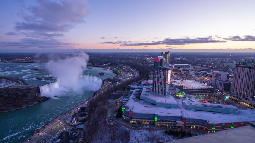 Aerial view of Niagara Falls City downtown horizon and Horseshoe Falls winter illumination. Time-lapse photography dusk to night. Ontario, Canada.