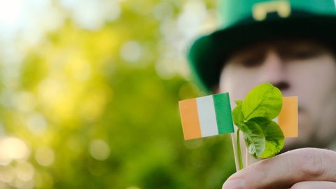 Four-leaf clover. Good luck symbol.Saint Patrick. clover leaf in the hand of a man in a green hat in a sunny spring garden.Irish traditional spring holiday